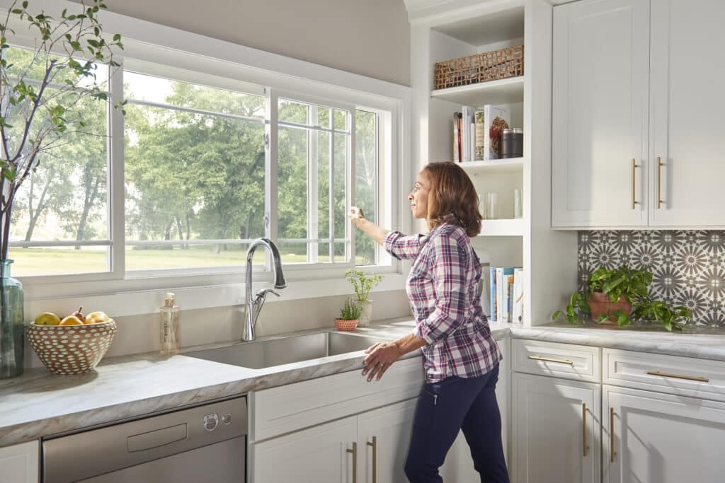 Woman in kitchen opening sliding window